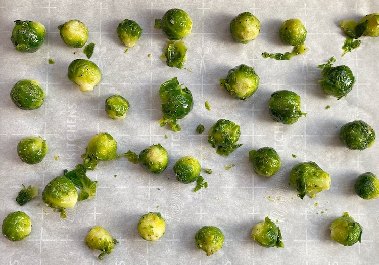 Steamed brussels sprouts on a baking sheet after being tossed with oil and seasoning. 