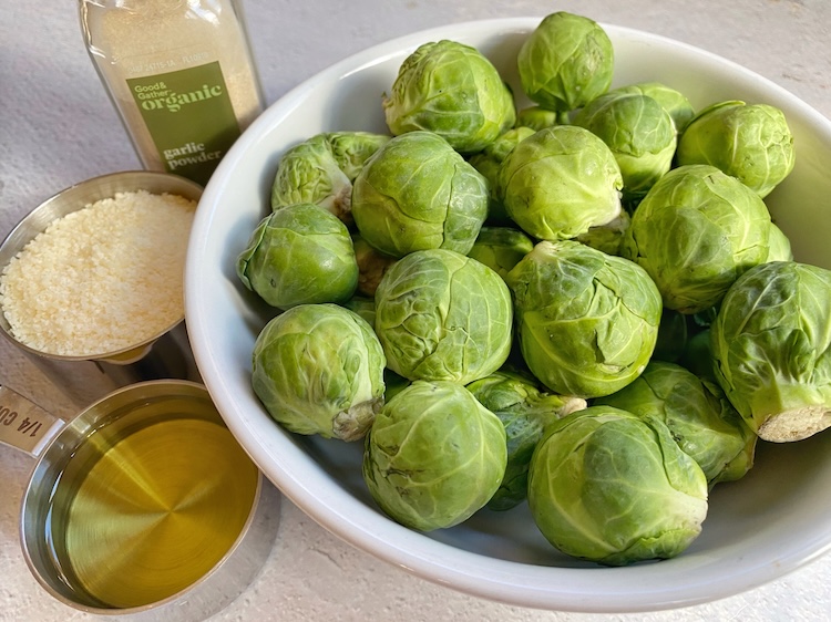 Ingredients for making oven roasted crispy smashed brussels sprouts: fresh or frozen brussels sprouts, olive oil, parmesan cheese and seasoning. 