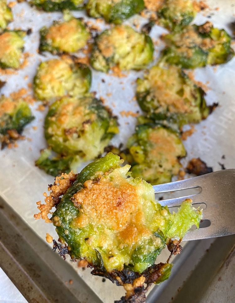 Up close picture of a crispy smashed brussels sprout on a fork just after being baked in the oven. 