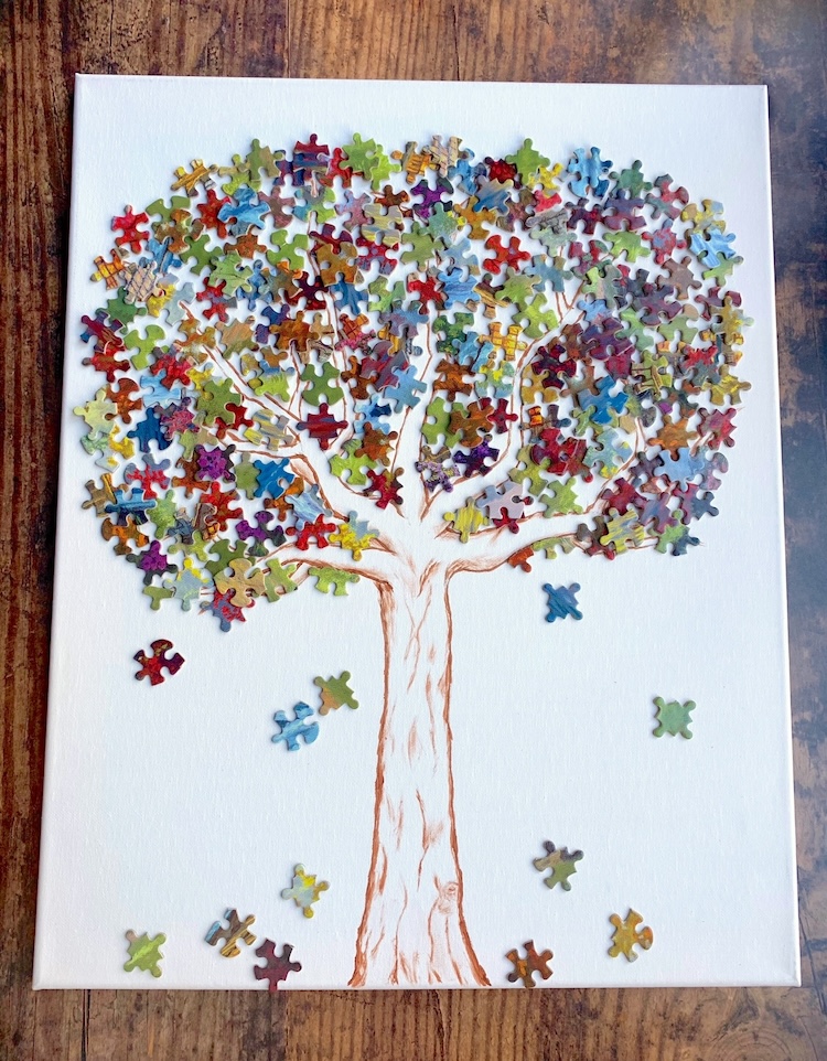 Leafy Tree Puzzle Piece Wall Art | If you're looking for cheap and easy projects to make, time to break out an old puzzle to make this gorgeous DIY wall art! Simply draw a tree trunk on a white canvas and then have fun gluing on colorful puzzle pieces to make the leaves. 