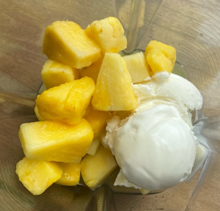 Pineapple chunk and vanilla ice cream in a blender ready to make Disney's Copycat Pineapple Dole Whip Recipe!