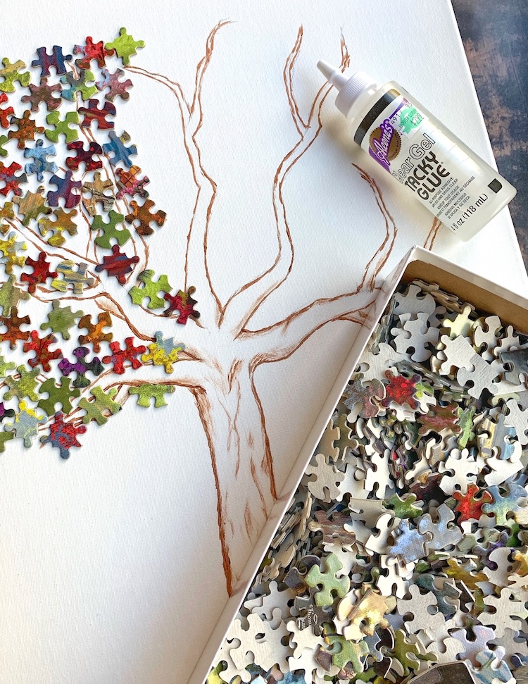 Are you looking for adult craft ideas? You've got to try this puzzle piece wall art! You'll just need a canvas, old puzzle pieces, glue, and paint. This creative and fun project makes art that you can actually be proud of. I made a leafy tree on a 16x20 canvas with small colorful puzzle pieces and a painted on tree trunk. 