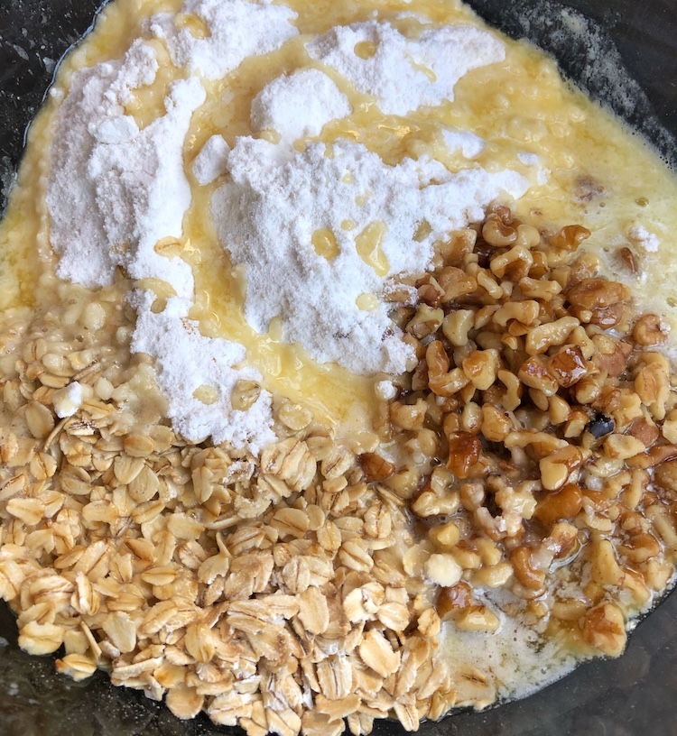 Betty Crocker yellow cake mix, oats, walnuts, and melted butter in a bowl ready to be topped onto a frozen berry cobbler. 