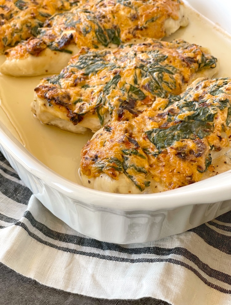 Baked Chicken Breasts in a baking dish topped with a mixture of cream cheese and sun dried tomatoes. 