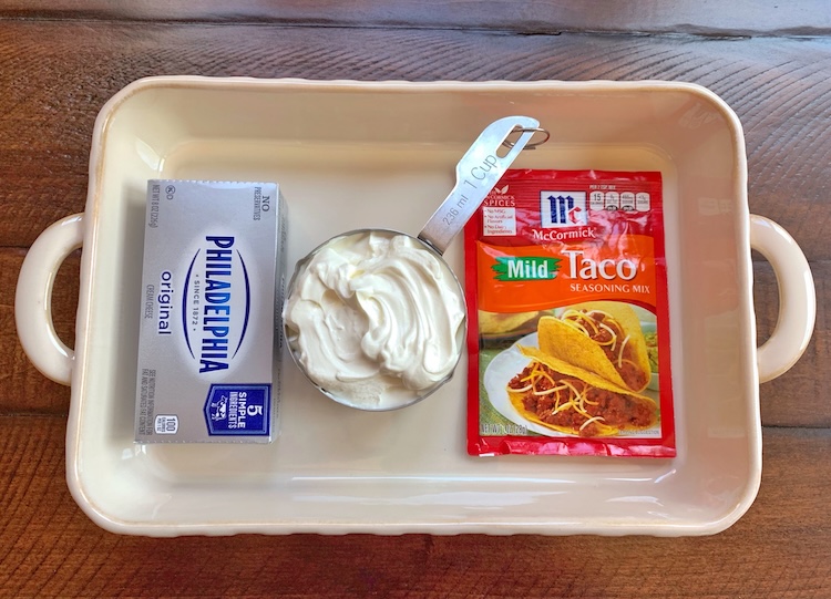 Cream cheese, sour cream, and taco seasoning ready to be blended to make the cold base for a delicious taco dip. 