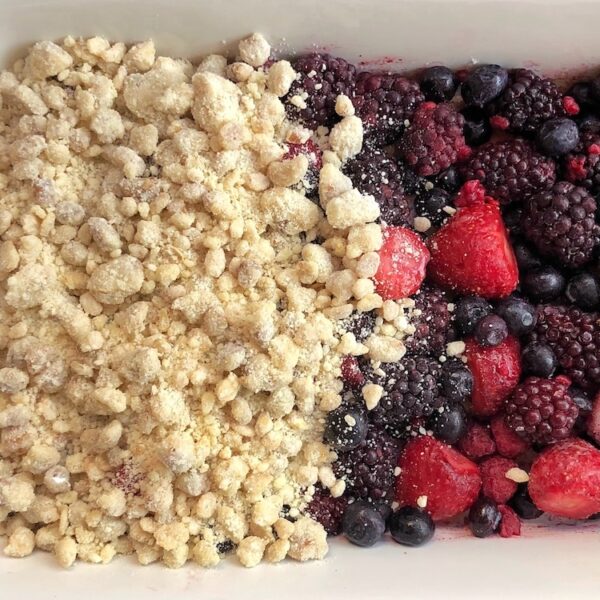 Frozen berries and a buttery cake mix topping ready to go into the oven to make the best berry cobbler dessert.