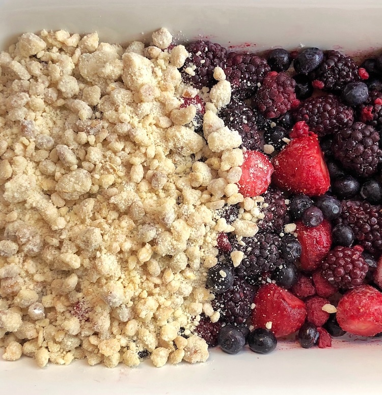 Frozen berries and a buttery cake mix topping ready to go into the oven to make the best berry cobbler dessert. 