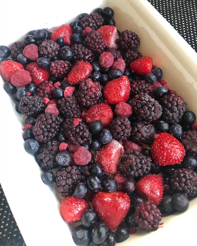 Mixed frozen berries in a baking dish ready for the oven to make the easiest ever berry cobbler with cake mix. 
