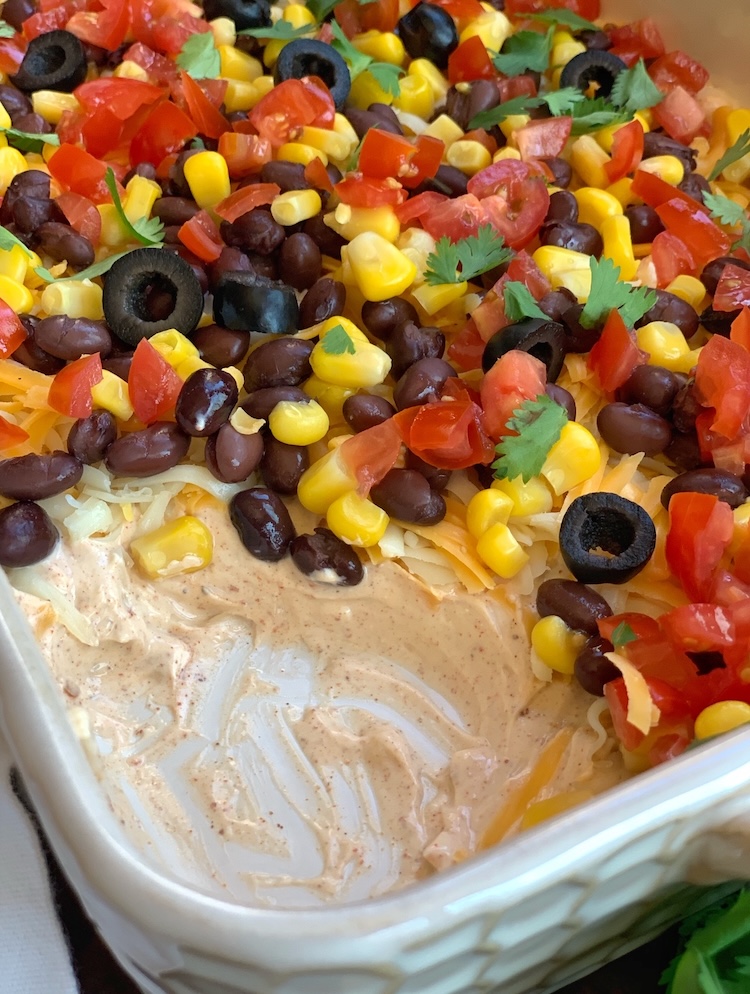 Close up view of a cream cheese taco dip topped with lots of fresh and vegetarian ingredients. 