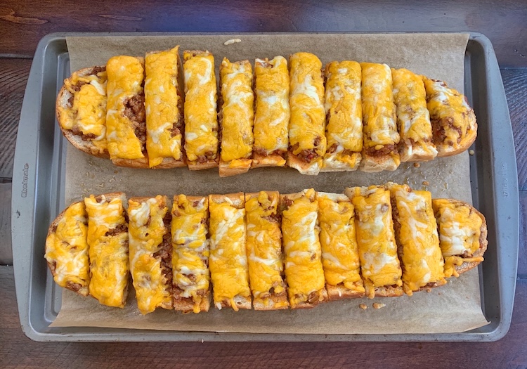 Cheesy Sloppy Joe French Bread Pizza on a baking dish cut into small handheld pieces ready to serve!